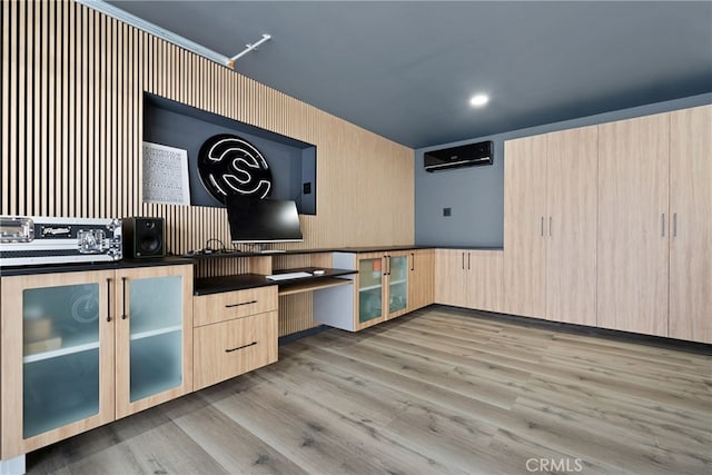 kitchen with a wall unit AC, light brown cabinetry, and light hardwood / wood-style floors