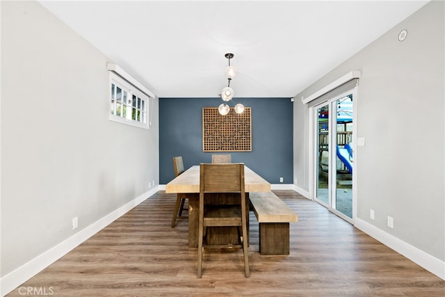 dining space with wood-type flooring, plenty of natural light, and an inviting chandelier