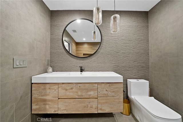 bathroom featuring tile walls, vanity, and toilet