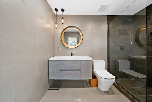 bathroom featuring a tile shower, tile walls, vanity, toilet, and tile patterned floors