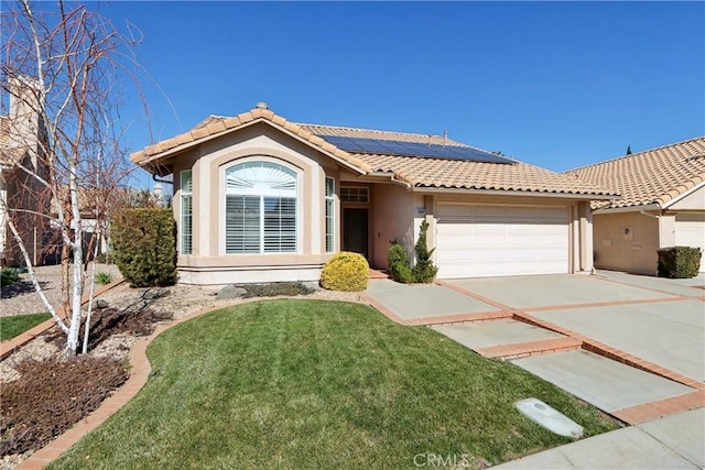 view of front of home with a garage, a front yard, and solar panels