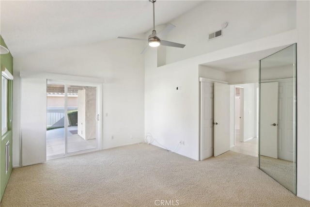 carpeted empty room with ceiling fan and high vaulted ceiling