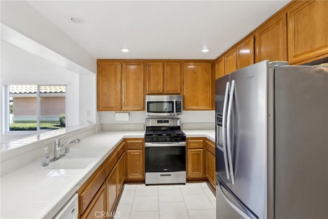 kitchen featuring tile countertops, appliances with stainless steel finishes, sink, and light tile patterned floors