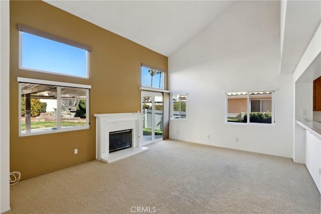 unfurnished living room featuring high vaulted ceiling, a wealth of natural light, light carpet, and a fireplace