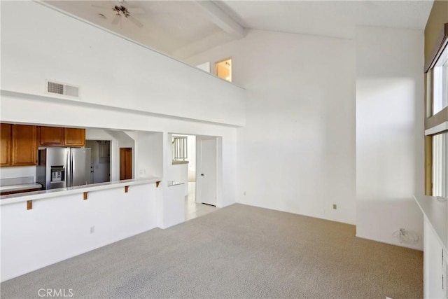 unfurnished living room featuring high vaulted ceiling, light carpet, and beam ceiling