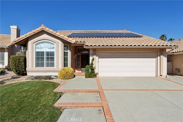 view of front facade featuring a garage, a front lawn, and solar panels