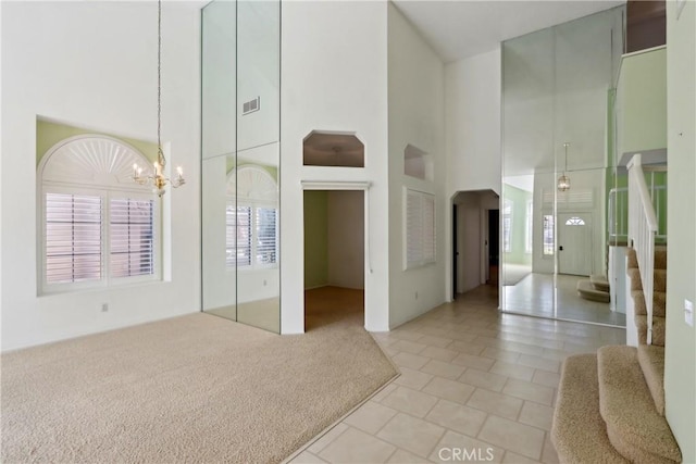 interior space with a towering ceiling, light carpet, and an inviting chandelier