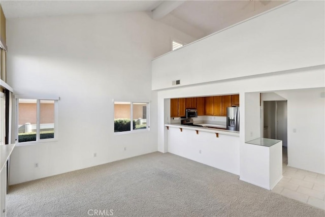 unfurnished living room featuring high vaulted ceiling, light carpet, and beam ceiling