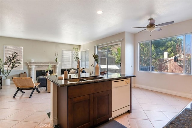 kitchen featuring dark stone countertops, sink, light tile patterned floors, and dishwasher