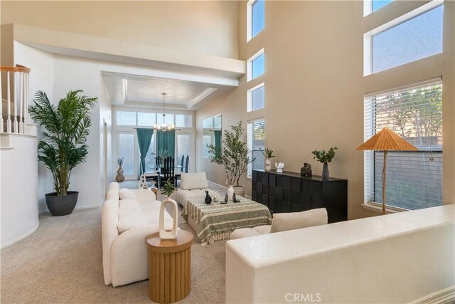 living room with a high ceiling, a wealth of natural light, a chandelier, and carpet