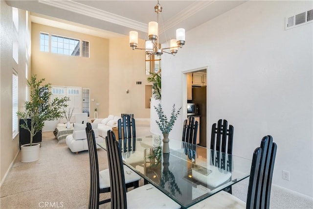 carpeted dining room featuring an inviting chandelier, ornamental molding, and a high ceiling