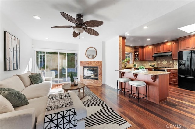 living room featuring a premium fireplace, dark hardwood / wood-style floors, and ceiling fan