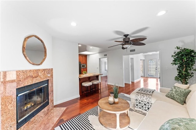 living room featuring ceiling fan, a premium fireplace, and hardwood / wood-style floors