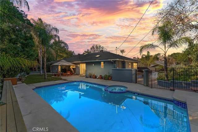 pool at dusk with an in ground hot tub, a gazebo, and a patio area