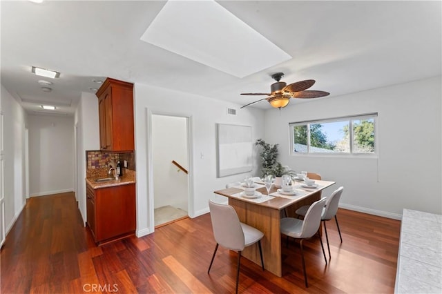 dining area with dark hardwood / wood-style floors, a skylight, and sink