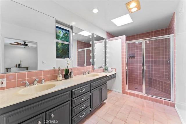 bathroom with vanity, a shower with shower door, backsplash, and a skylight