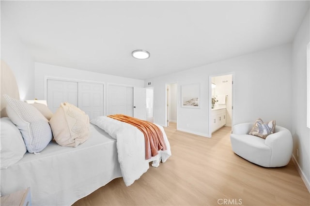 bedroom featuring multiple closets and light hardwood / wood-style floors