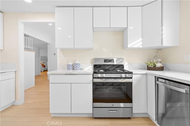 kitchen featuring appliances with stainless steel finishes, white cabinets, and light wood-type flooring