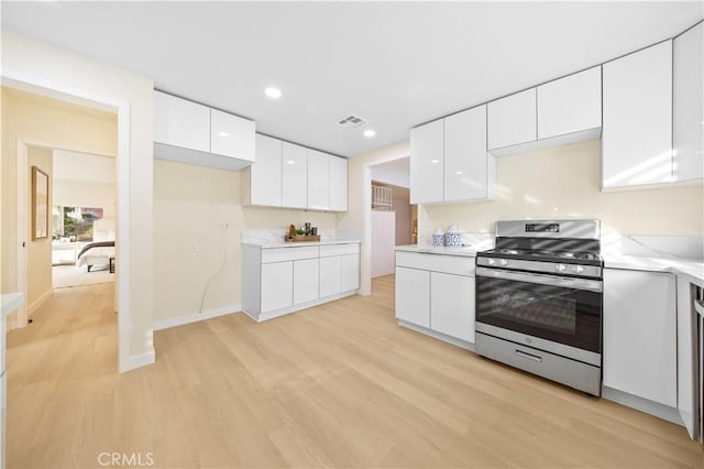 kitchen with stainless steel range with gas cooktop, light hardwood / wood-style flooring, and white cabinets