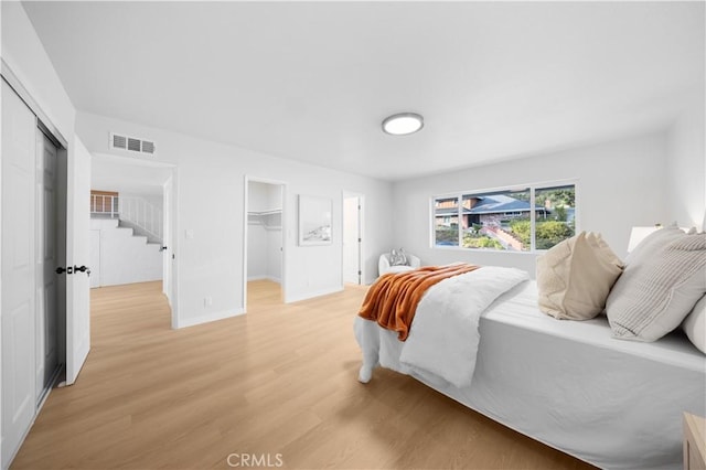 bedroom with a closet, a walk in closet, and light hardwood / wood-style flooring