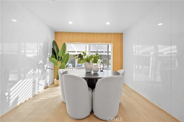 dining space with wood walls and light wood-type flooring