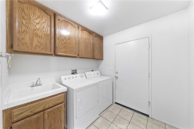 washroom featuring sink, washer and clothes dryer, cabinets, a textured ceiling, and light tile patterned flooring