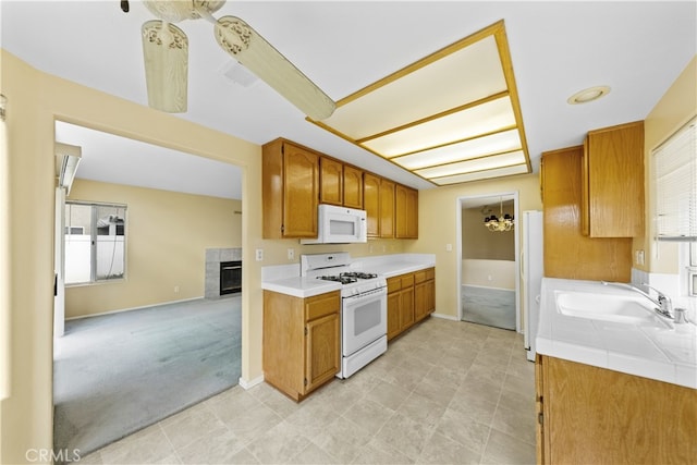 kitchen with sink, light colored carpet, a fireplace, and white appliances