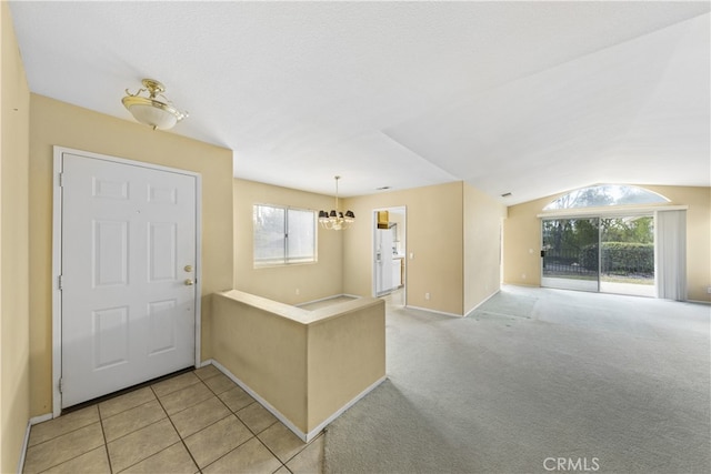 foyer entrance with light colored carpet and a notable chandelier