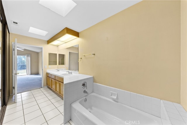 bathroom with vanity, a washtub, tile patterned flooring, and a skylight