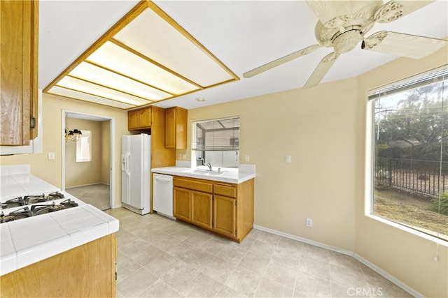 kitchen with ceiling fan, white appliances, tile counters, and sink