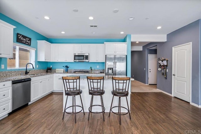 kitchen with stainless steel appliances, dark hardwood / wood-style floors, a center island, and white cabinets