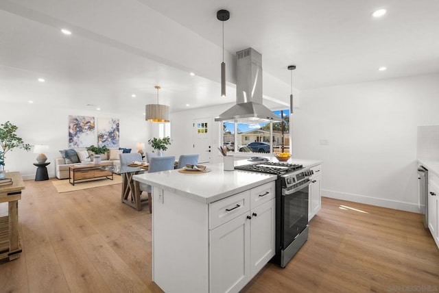 kitchen with white cabinetry, island range hood, stainless steel range with gas cooktop, and decorative light fixtures