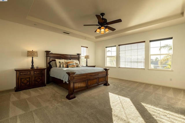 bedroom with a tray ceiling, ceiling fan, and carpet flooring