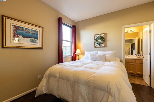 bedroom featuring ensuite bathroom and dark hardwood / wood-style floors