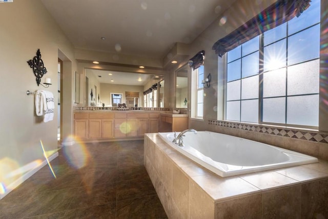 bathroom with vanity, a relaxing tiled tub, and tile patterned floors