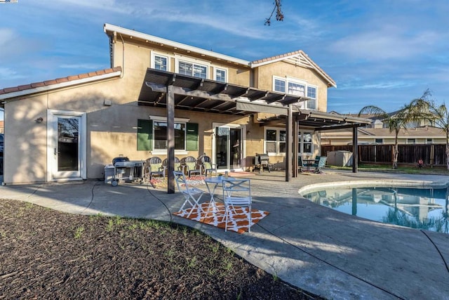 rear view of house featuring a fenced in pool, a pergola, and a patio area