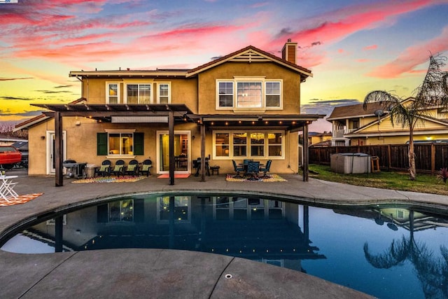 back house at dusk with a pool with hot tub and a patio