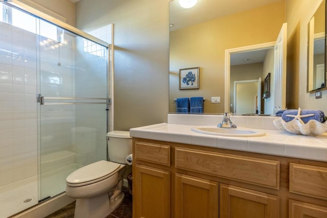 bathroom featuring vanity, a shower with shower door, and toilet