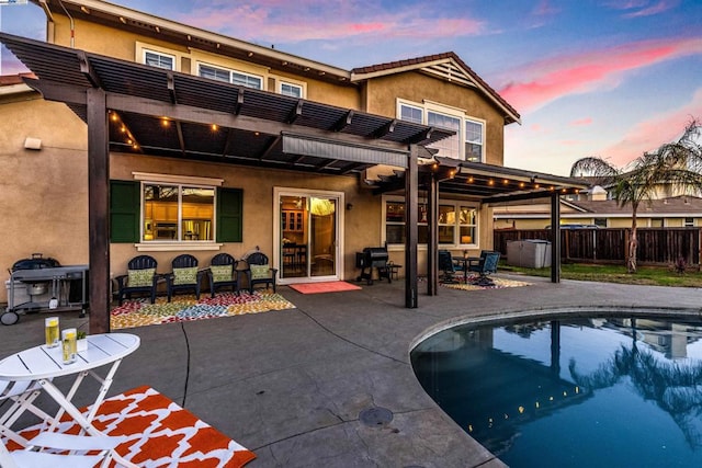 back house at dusk featuring a pergola, a fenced in pool, and a patio