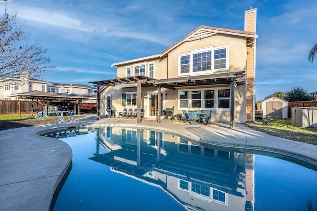 rear view of property featuring a fenced in pool, a pergola, and a patio area