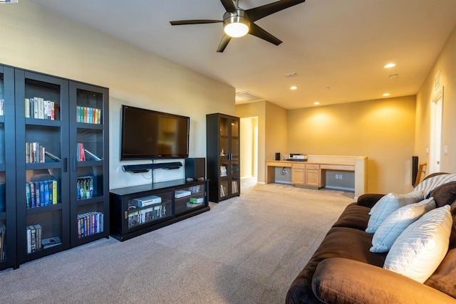 carpeted living room featuring ceiling fan and built in desk