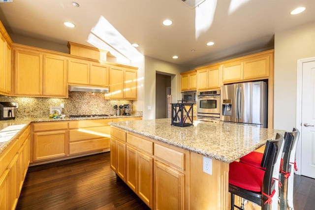 kitchen with dark hardwood / wood-style floors, a kitchen bar, a center island, exhaust hood, and stainless steel appliances