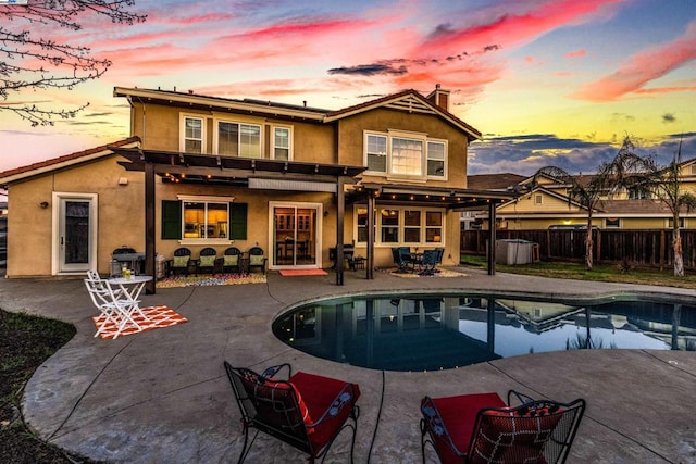 back house at dusk with a fenced in pool, a pergola, and a patio area