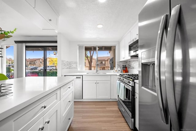 kitchen featuring appliances with stainless steel finishes, sink, white cabinets, and light hardwood / wood-style floors