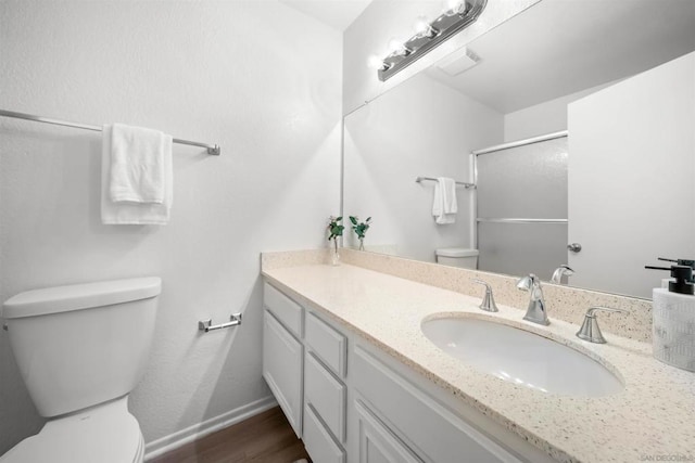 bathroom with hardwood / wood-style flooring, vanity, an enclosed shower, and toilet