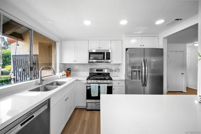 kitchen featuring sink, tasteful backsplash, light hardwood / wood-style flooring, appliances with stainless steel finishes, and white cabinets