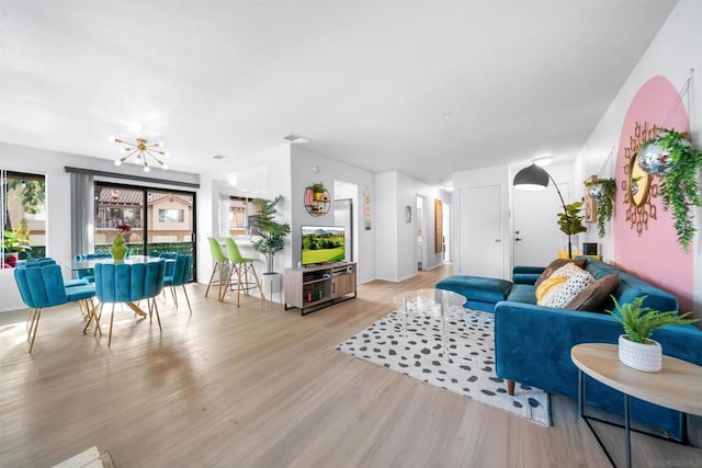 living room with an inviting chandelier and light wood-type flooring