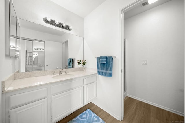 bathroom with vanity, hardwood / wood-style flooring, and a shower with door