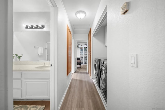 corridor featuring light hardwood / wood-style floors, washer and clothes dryer, and sink