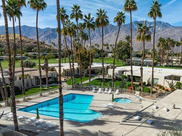 view of swimming pool featuring a community hot tub, a mountain view, and a patio